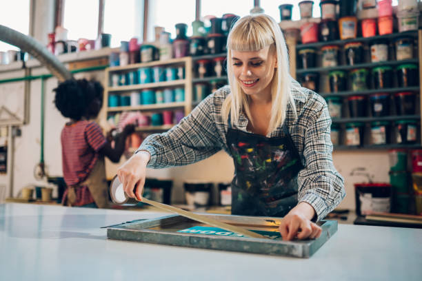 istock Smiling female graphic industry worker preparing screen printing plate 2139294830