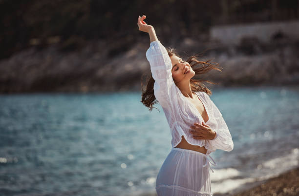 A beautiful woman having fun on the pebbles by the sea to get rid of the negativity of the whole week.