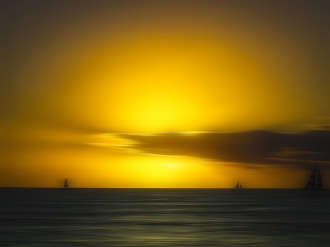 Seascape sunset in silhouette with sailboat and dramatic sky by blurred motion and long exposure