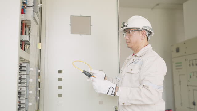 A person is using a multimeter to test electrical equipment