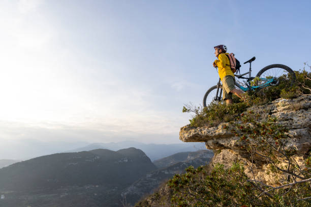 istock Mature mountain biker pauses on cliff edge 2139356223