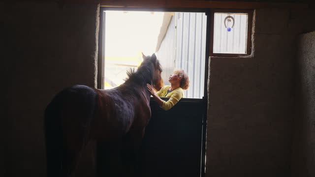 The female caretaker loves the horse in the stable.