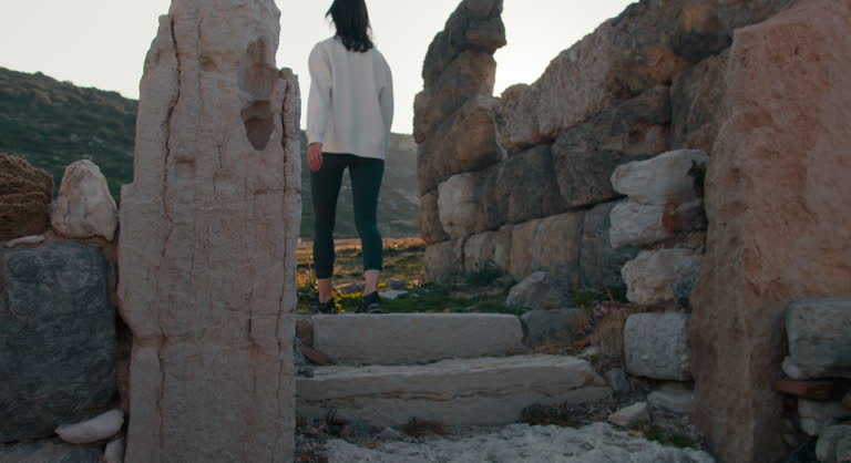Young tourist woman walking among greek ruins in ancient city