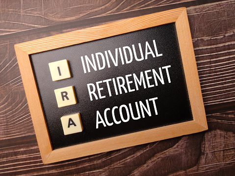 Toys word and wooden frame with the word INDIVIDUAL RETIREMENT ACCOUNT on a wooden background.
