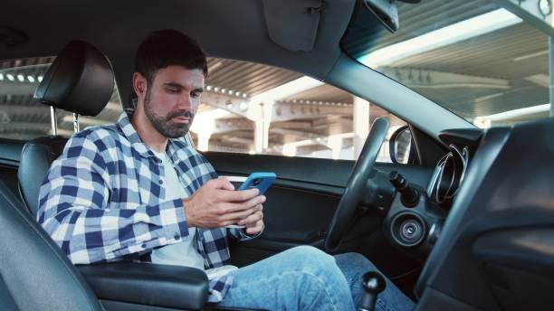 istock Young man typing on the mobile phone, hold coffee in the car. Slow motion 2139441519