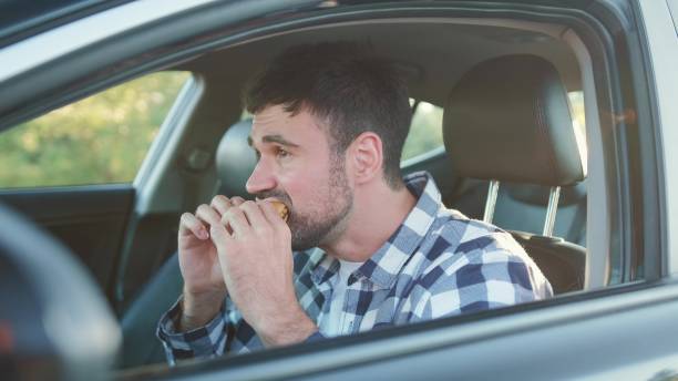 istock Young man eating burger, sitting in the car. Slow motion 2139441935