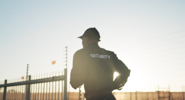 Security guard, running and man for outdoor patrol inspection, investigation and property search by fence. Surveillance, law enforcement and back of person for safety, crime and protection service