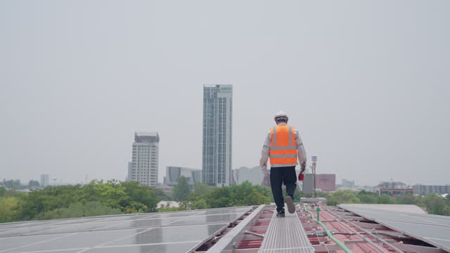 A man in an orange vest walks on a rooftop