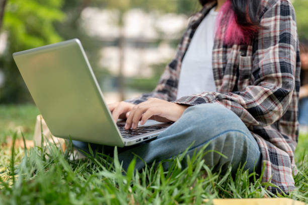 istock A cropped image of a female using her laptop computer while sitting on the grass in a park. 2139582520