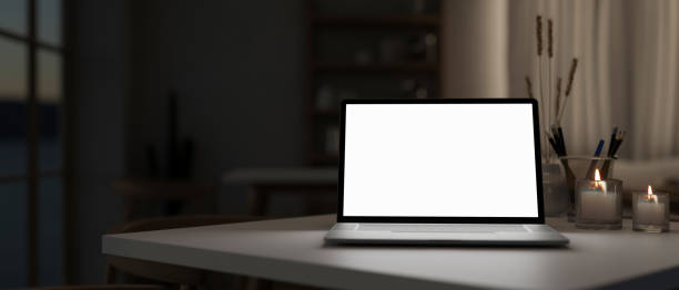 istock A white-screen laptop computer mockup on a table in a modern dark room. 2139584350
