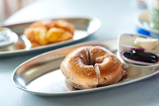 Freshly baked bagels are served with cream cheese and blueberry jam on a plate, making for a delicious breakfast option.