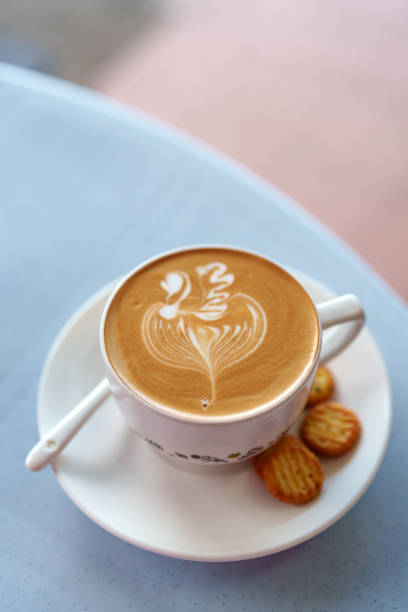 From a high angle view, a cup of coffee latte and crackers are served on a table in a local cafe during the morning.
