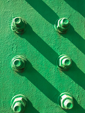 close-up view green-painted bolts and the shadow