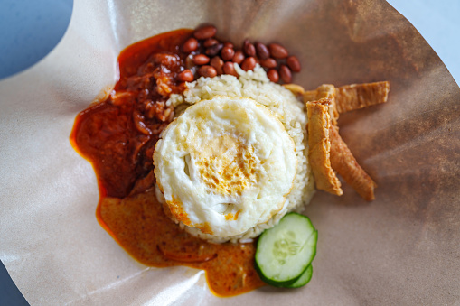 Nasi Lemak is a popular Malaysian street food known for its fragrant coconut rice served with various accompaniments like fried anchovies, peanuts, boiled egg, cucumber slices, and spicy sambal.