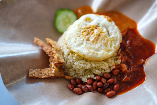 Nasi Lemak is a popular Malaysian street food known for its fragrant coconut rice served with various accompaniments like fried anchovies, peanuts, boiled egg, cucumber slices, and spicy sambal.