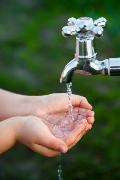 boy washes his hand under the faucet in garden