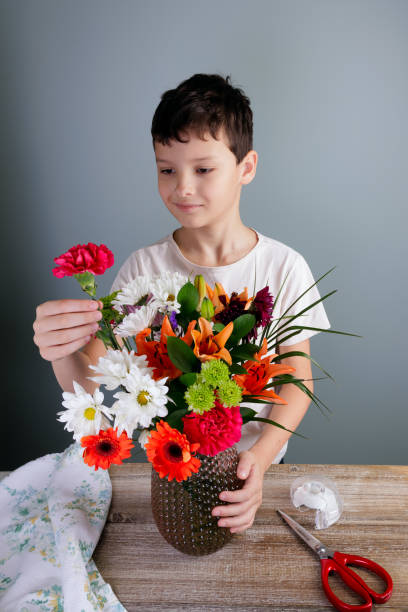 自宅の花瓶に花を生けて花を生けている若い花屋さん。 - carnation mothers day florist flower ストックフォトと画像