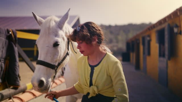 Woman leading the white horse outside by its reins.