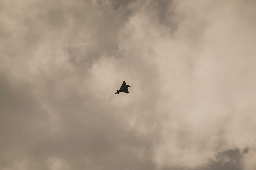 single loud slow flying fighter jet on a cloudy sky