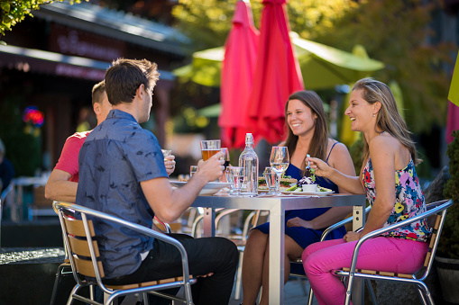 Friends enjoy meal at outdoor cafe in summer