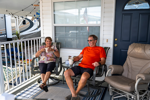 Mature couple enjoy hot beverage on porch of mobile home