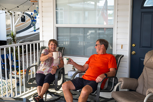 Mature couple enjoy hot beverage on porch of mobile home
