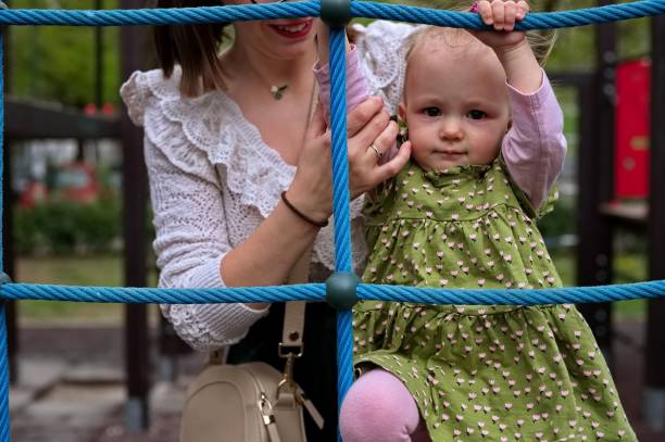 istock Mother and daughter on playground ladder 2139888492