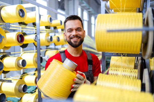 istock Portrait of textile factory worker changing thread material on industrial knitting machine. 2139909699