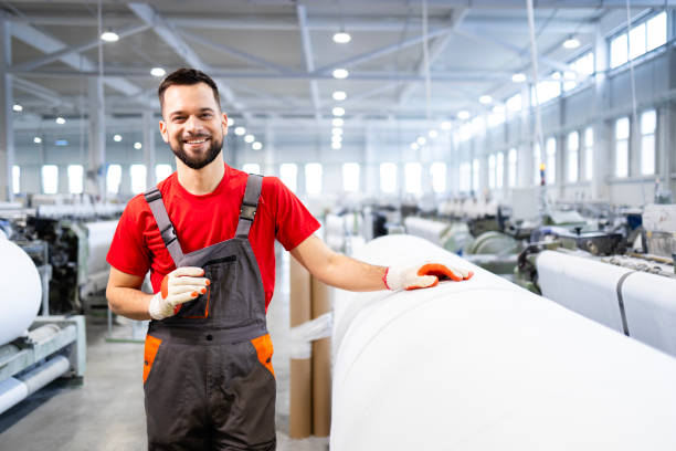 istock Portrait of experienced worker standing by machine and checking carpet production inside textile factory. 2139910454