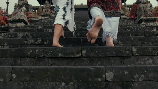 Tourists walking barefoot on the steps leading to the temple