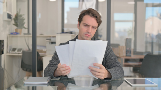 Middle Aged Man Reading Business Report at Work