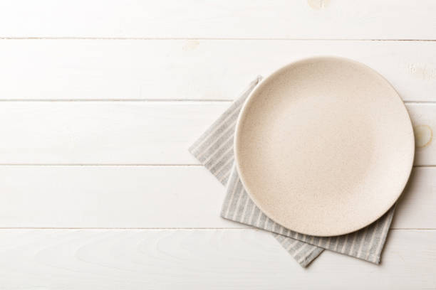 istock Top view on colored background empty round white plate on tablecloth for food. Empty dish on napkin with space for your design 2139930626