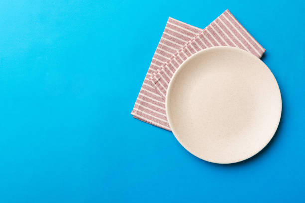 istock Top view on colored background empty round white plate on tablecloth for food. Empty dish on napkin with space for your design 2139930633