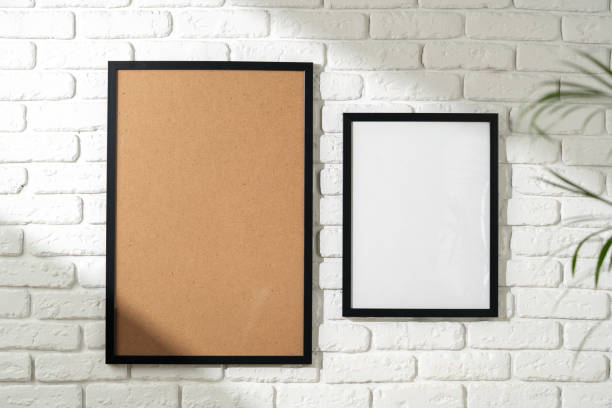 istock Two Empty Picture Frames Hanging on a White Brick Wall With a Plant in the Foreground 2139951288