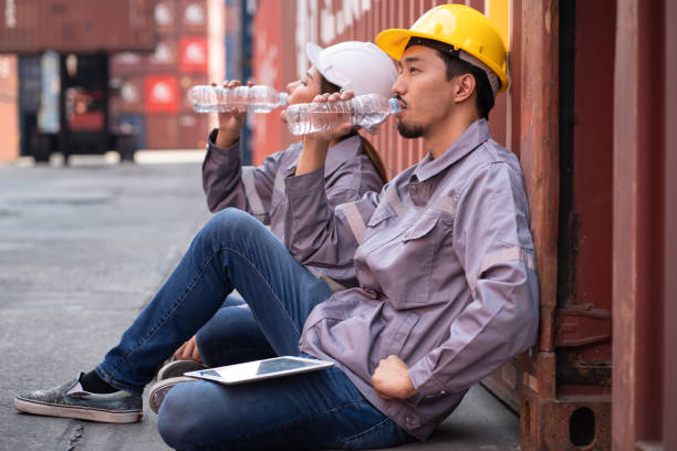 istock Very tired and Asia logistic engineer man worker or foreman with engineer woman drinking pure water at container site 2139967801