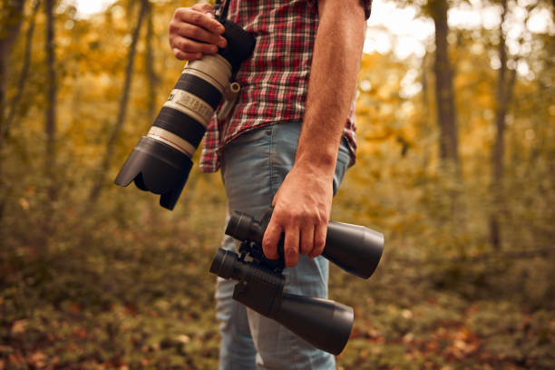 Man using binoculars and camera for birdwatching and other observing animals in nature.