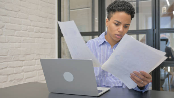 istock Young African Woman Working on Documents and Laptop 2139989590