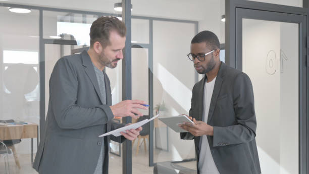 istock Standing Multi Ethnic Teammates Discussing Business Report 2139991202