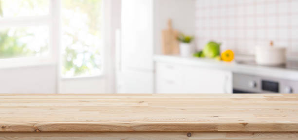 istock Wooden table top with copy space on blurred kitchen room interior and summer window background 2140055264