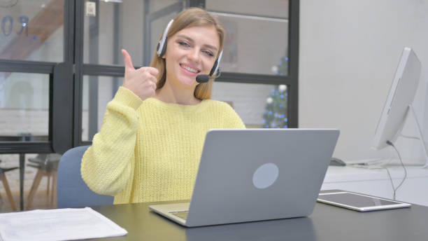 istock Thumbs Up by Female Call Center Employee with Headset at Work 2140060629