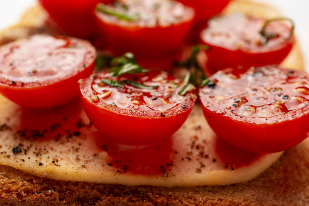 Healthy nutrition stock photo. Tomato toast, basil leaves, pepper, spices and garlic cloves on wood plate closeup angle view