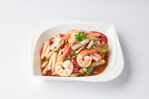 Lotus roots spicy salad with prawns served on a white plate isolated on white background.