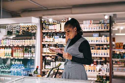 A female African customer browses the selection of frozen products in the organic convenience store