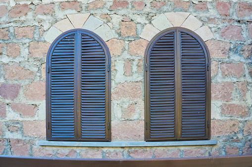 Windows with closed wooden shutters in a stone wall