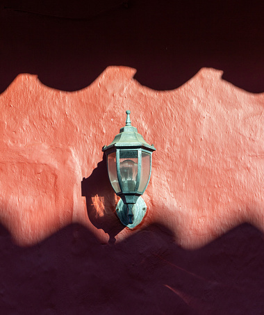 Street lamp on a red wall, between shadow and light. Artistic minimalist photography.