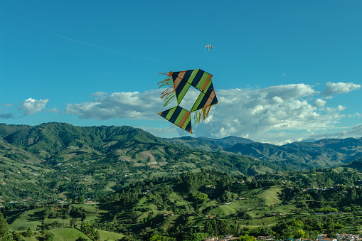 Colored kite in a blue sky with the Andes Mountains in the background during the Festival de la cometa (English : kite festival) in Jerico, Antioquia, Colombia.