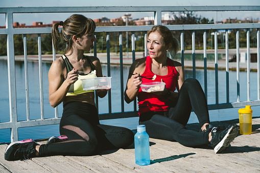 Two women eating in the park after training