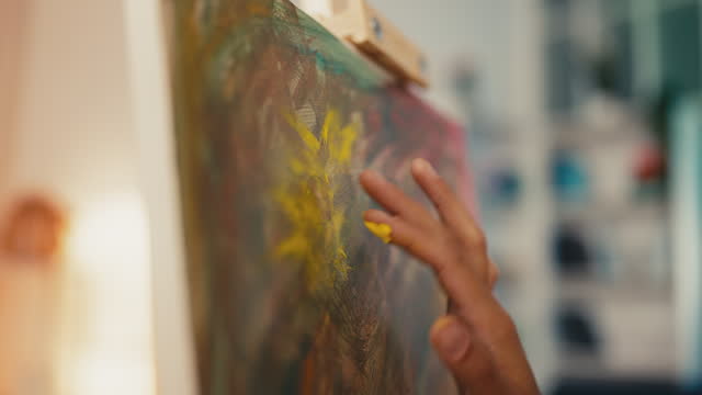Close-up of woman artist painting with hands on canvas, mixing colors, hobby