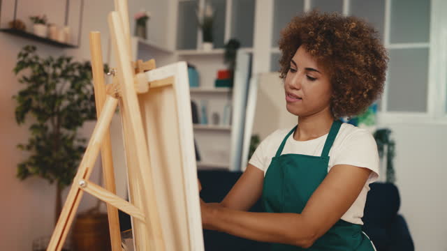 Creative African American woman artist painting a picture with her hands, art