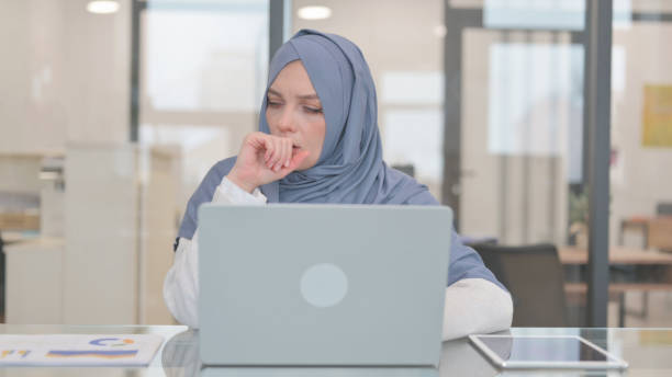 istock Coughing Arab Woman Using Laptop in Office 2140193284